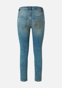 Jean skinny bleu en denim avec un effet délavé, doté de deux poches arrière et de coutures décoratives sur la poche droite.