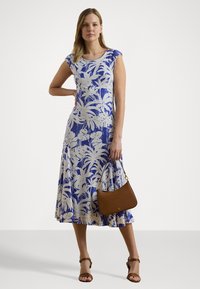 Šaty s květinovým potiskem v modro-bílé barvě, ke kolenům s krátkými rukávy. Hnědá kabelka a hnědé sandály doplňují outfit. Hladký textilní materiál.