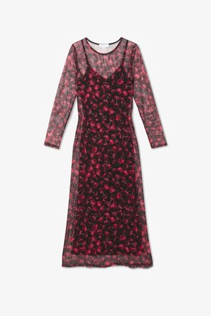 Largo vestido negro transparente con vibrante estampado de cerezas rojas y mangas largas, superpuesto a un vestido de tirantes a juego con estampado de cerezas.