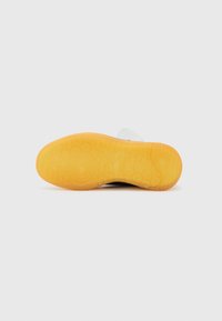 Talpa de pantof din cauciuc cu un model texturat galben, având o parte superioară albă și un accent lateral negru. Elementele de design sunt rotunde și circulare.