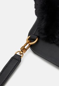 Borsa nera con un accento in pelliccia sintetica testurizzata e pelle liscia. Presenta una chiusura in metallo dorato e una tracolla removibile.