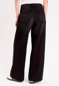 Bredde ben sorte denim jeans med høj talje, der har to baglommer og en ren finish uden udsmykning.