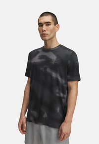 Camiseta deportiva negra con un patrón abstracto sutil, de mangas cortas y cuello redondo. Fabricada con un tejido ligero que absorbe la humedad.