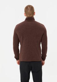 Pullover marrone lavorato a maglia con un collo alto, maniche lunghe e un tessuto testurizzato. Dettagli delle cuciture sulle spalle e sui polsini.