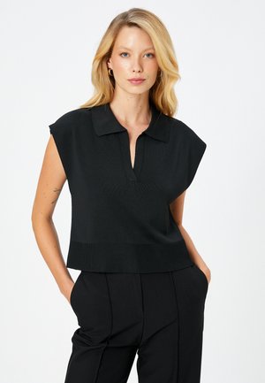 Top sin mangas negro con cuello, presenta un escote en V y dobladillo acanalado. La textura es suave, con un corte holgado adecuado para el uso diario.
