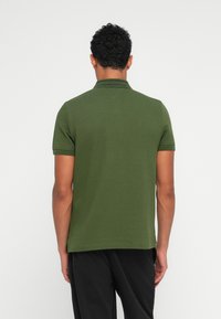 Grønn polo skjorte med korte ermer, teksturert stoff og krage. Har en rett kant og minimalistisk design.