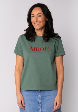 Groene katoenen T-shirt met rode opdruk "Amore" op de borst, ronde halslijn en korte mouwen. Gecombineerd met een denim rok.
