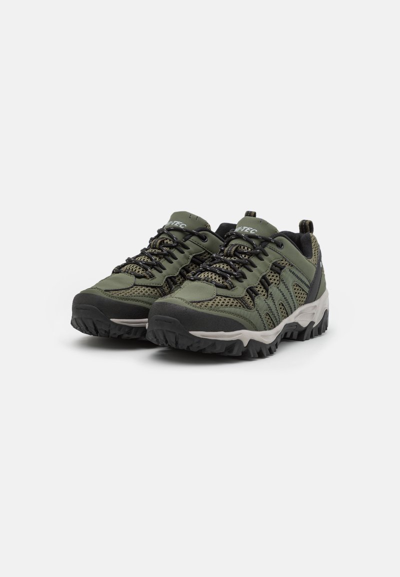 Scarpe da trekking con tessuto e gomma verde scuro, punta rinforzata, pannelli in rete testurizzata e suola nera robusta.