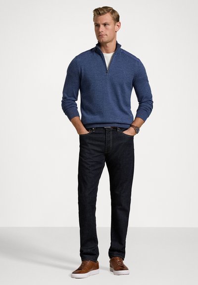 Blue zip-neck sweater, dark jeans, brown shoes. Sweater features ribbed cuffs and hem, textured fabric, and a fitted design.