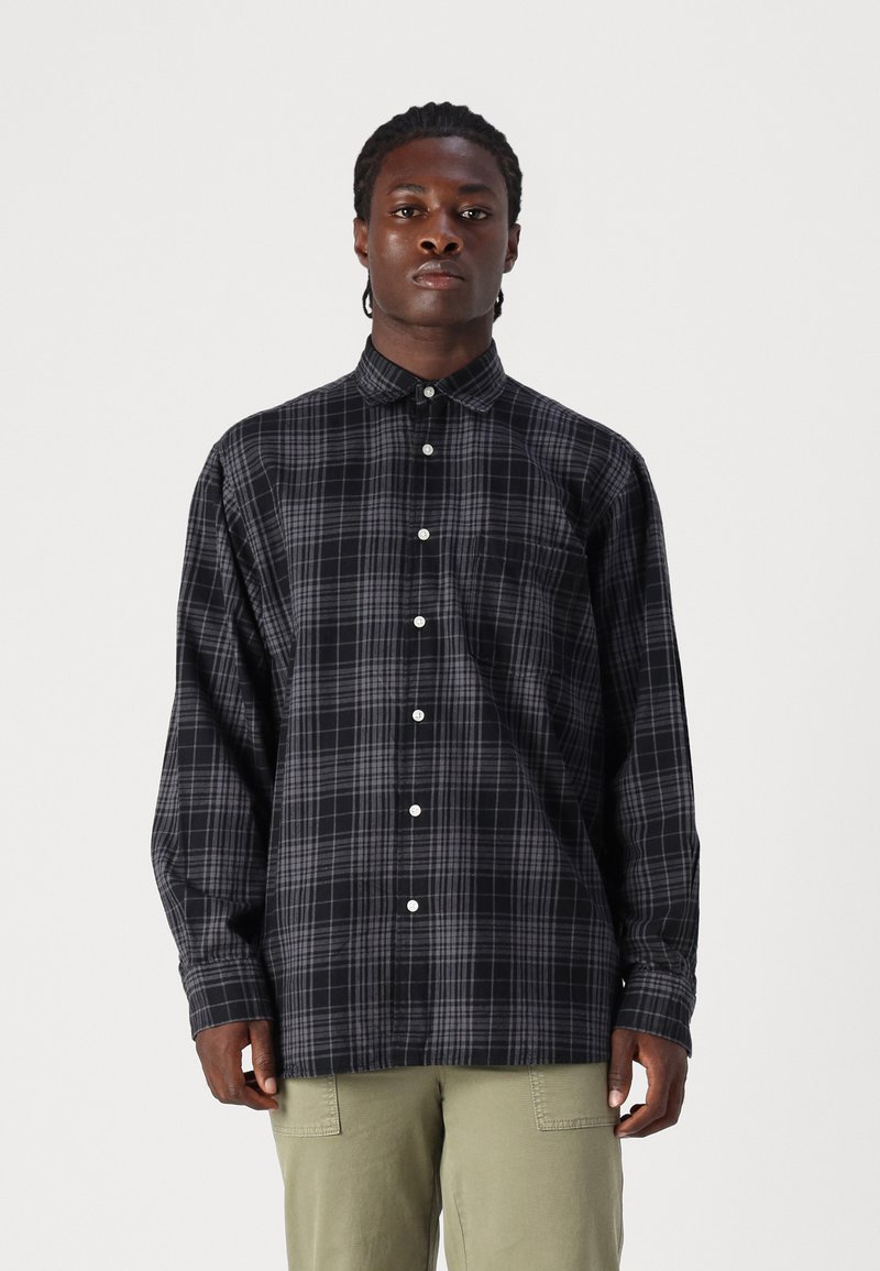 Camisa de cuadros de manga larga en negro y gris, con cuello abotonado y botones blancos. Fabricada en una tela ligera, de corte relajado.
