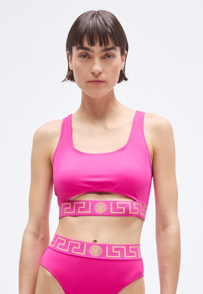 Pink two-piece swimwear set featuring a cropped top with a cutout and gold patterned band, accented by a matching high-waisted bottom.