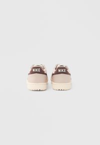 Καφέ και μπεζ αθλητικά παπούτσια Nike με υφή στη λαστιχένια σόλα, στρογγυλεμένο σχήμα, μαξιλαρωμένο πέλμα και λογότυπο στη φτέρνα.