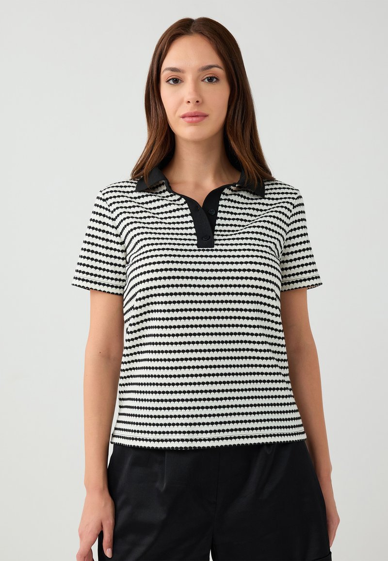 Zwart-wit gestreepte polo shirt met korte mouwen, gestructureerde stof en zwarte kraag. Bevat een drieknopenlijst bij de hals.