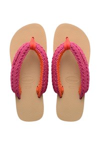 Des tongs en tissu tressé rose et orange, avec une semelle en caoutchouc texturé de couleur beige et un entre-doigt central, présentant un motif de vagues sur la base.