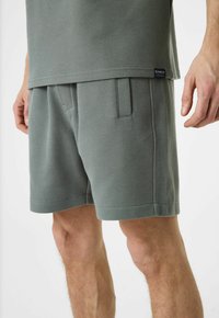 Grijs T-shirt met korte mouwen en bijpassende shorts gemaakt van gestructureerde stof, met een ruitpatroon, zijzakken en een klein logootje.