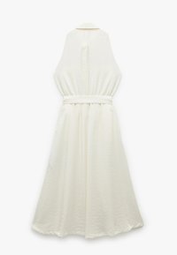 Vestido blanco sin mangas con una sutil textura en la tela, presenta un cuello con solapa, cintura ceñida y una fluida silueta en forma de A.