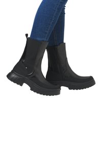 Bottines noires à la cheville avec un dessus texturé, des panneaux latéraux élastiques et une semelle épaisse. Équipées d'une fermeture éclair lisse et d'un bout renforcé.