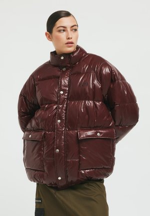Burgundy puffer jacket with a glossy finish, high collar, snap buttons, and two front pockets. Features a subtle logo on the chest.