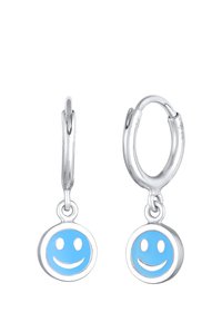 Sølv hoops øreringe med blå smiley ansigt charms. Charms har en glat overflade med hvide smil detaljer, hængende fra polerede hoops.