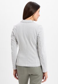 Striped blazer in white and light gray fabric, tailored fit, long sleeves, with a notched collar and subtle textured pattern.