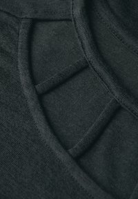 Tessuto a maglia nero con superficie texture, caratterizzato da un collo a strati e dettagli di cucitura a contrasto.