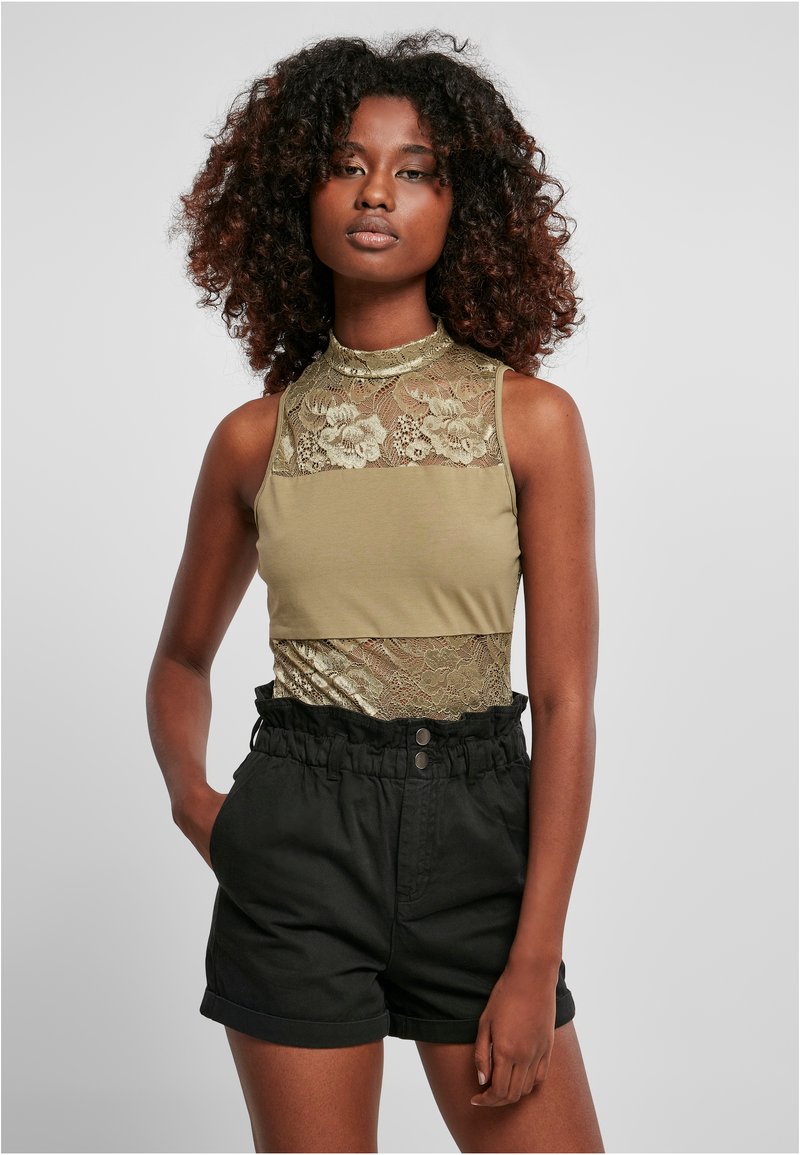 Top sin mangas color oliva con detalle de encaje floral y una capa inferior metálica dorada, combinado con pantalones cortos negros de talle alto con una cinturilla fruncida.