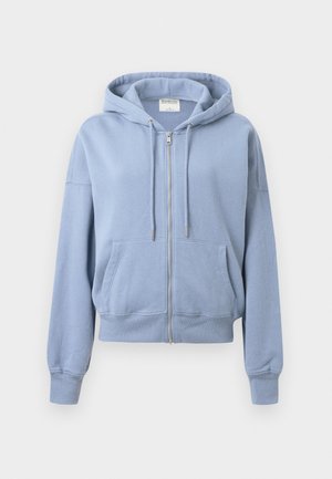 Sweat à capuche zippé bleu clair avec poches avant, cordon de serrage au niveau de la capuche et poignets côtelés, présenté sur un fond blanc uni.
