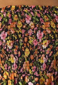 Schwarzer Stoff mit geraffter Textur, der ein dichtes Muster aus kleinen rosa, orangefarbenen, gelben und grünen Blumenprints zeigt.