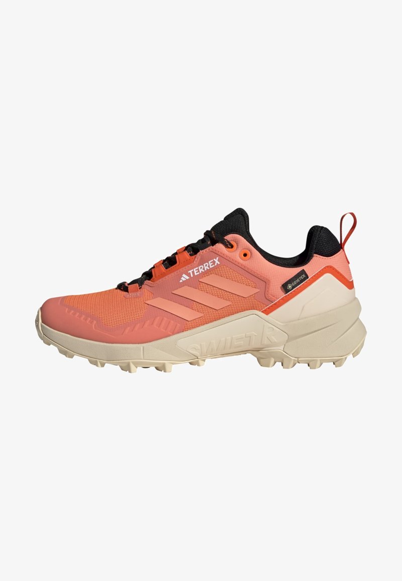 Chaussure de trail running légère en corail avec une tige en mesh durable, des accents noirs, une semelle rembourrée et un motif de grip texturé sur la semelle extérieure.