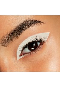 Närbild på ett öga med tjock vit eyeliner som formar en skarp vinge, som kontrasterar mot den mörkbruna iris och fylliga ögonfransar, med en naturlig hudstruktur.