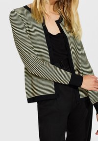 Černobílý kardigan s kostkovaným vzorem houndstooth, kulatým výstřihem, dlouhými rukávy a pevným černým lemem. Přední knoflíky a uvolněný střih.