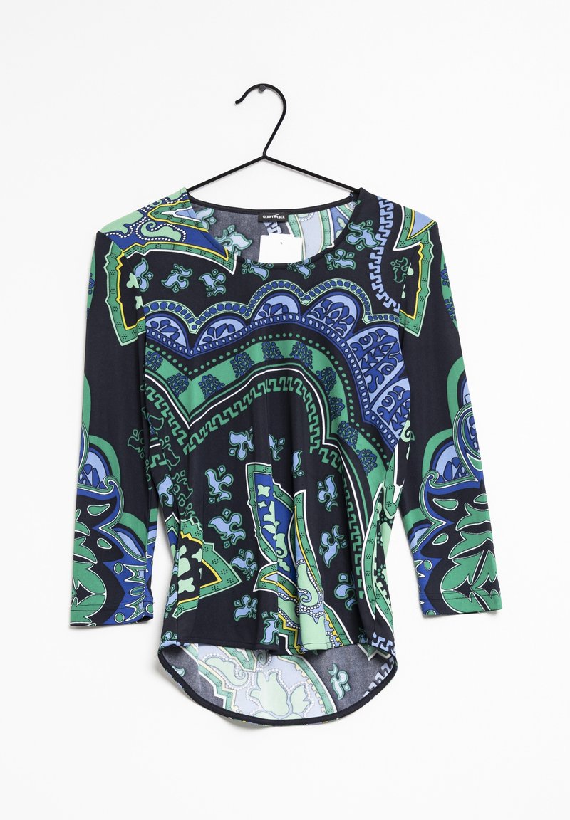 Haut noir à manches longues avec des motifs géométriques et floraux colorés en vert et bleu. Présente un col rond et un ourlet légèrement arrondi.