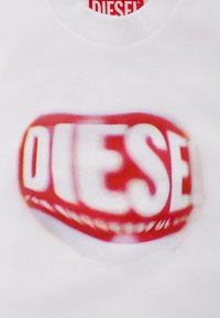 Felpa bianca con logo "DIESEL" sfocato rosso e bianco al centro. Realizzata in tessuto morbido con scollatura a girocollo.