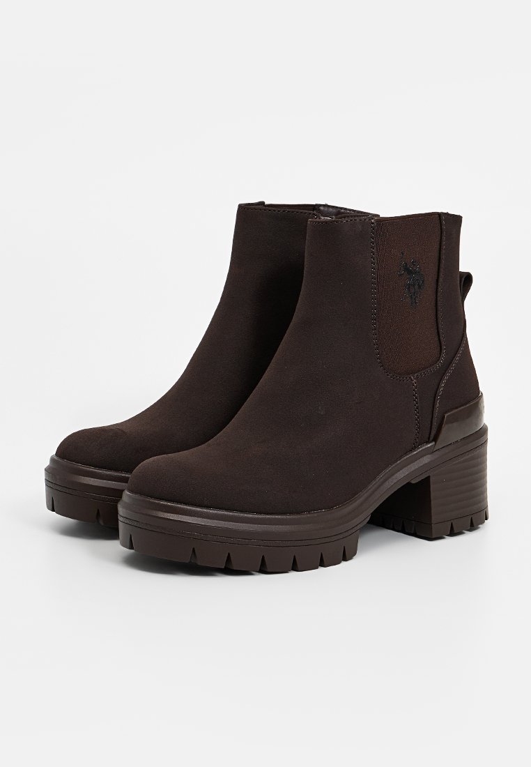 Braune Stiefeletten aus Wildleder mit einem dicken Absatz, elastischen Seiteneinsätzen und einer geriffelten Sohle. Verfügt über ein dezentes Logo an der Seite.