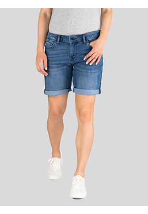 Denim shorts in medium blue with rolled cuffs, featuring a classic five-pocket design and a button-fly closure. Worn with white sneakers.