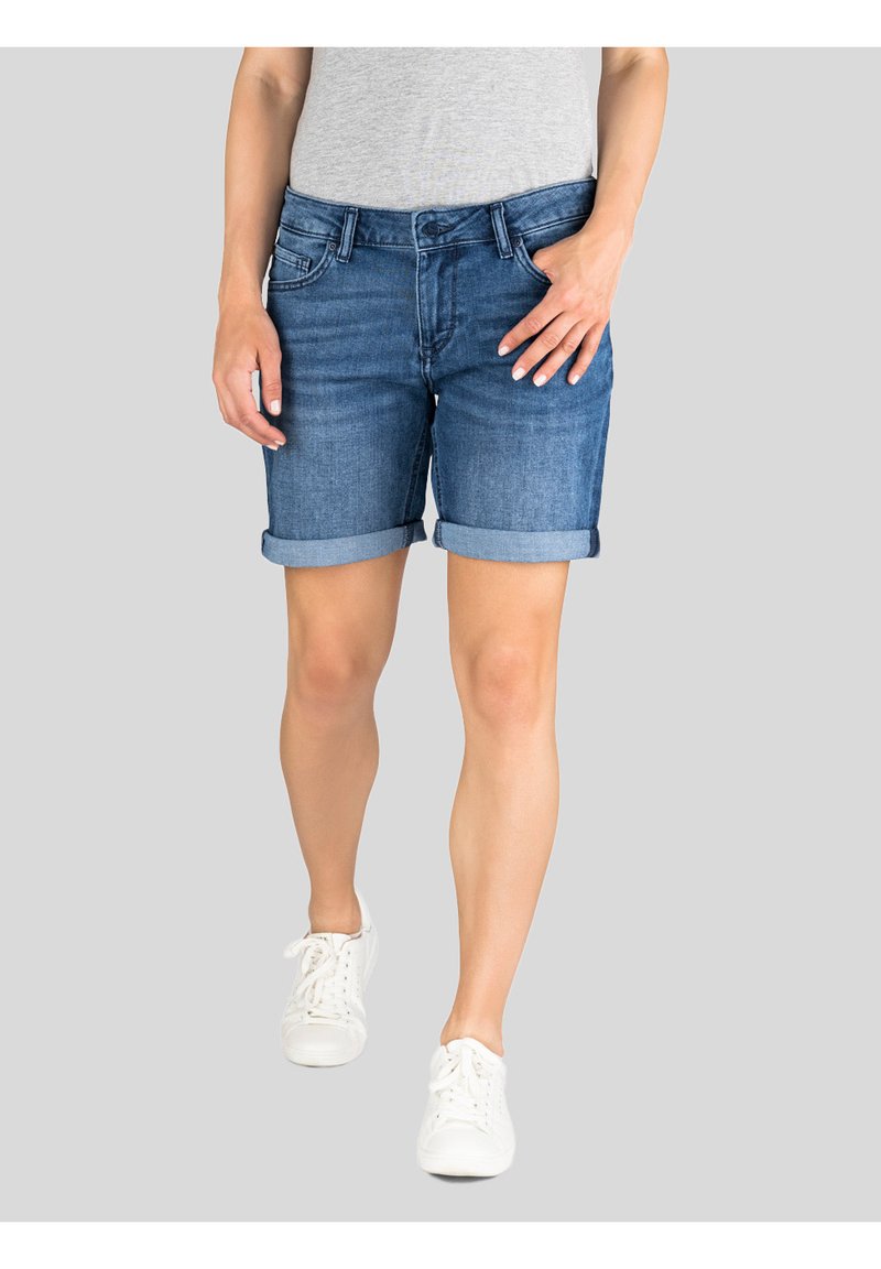 Denim shorts in medium blue met opgerolde boorden, voorzien van een klassiek vijf-pocket ontwerp en een knoopsluiting. Gemaakt met witte sneakers.