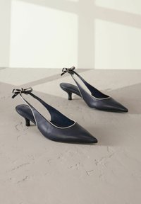 Merihenkinen nahkainen slingback-korkokengät, joissa on teräväkärkinen muotoilu, vaaleanpunainen yksityiskohta ja koristeellinen rusetti nilkassa. Alhainen kitten-korko.