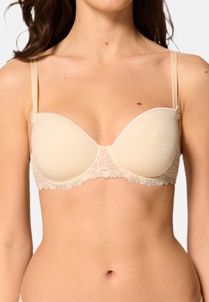 Beige gevoerde bh met kantafwerking; heeft verstelbare bandjes en een gladde textuur. Inclusief decoratieve accenten in het midden en op de bandjes.