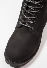 Černá kožená bota s robustní gumovou podrážkou, pevným tkacím systémem, stříbrnými očky a hladkým matným povrchem na svršku.