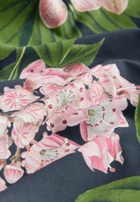 Blommönstrad tyg i mörk marinblå med rosa blommor och gröna blad. Mjuk textur med detaljerade blommönster och subtil skuggning.