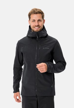 Giacca softshell nera con zip frontale, cappuccio regolabile e tasche. Presenta una texture liscia e un design minimal con accenti sottili.