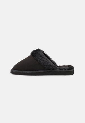Sorte slip-ons lavet af blødt suede med en fluffy grå foring og en tekstureret sort sål, der har et afrundet tådesign.
