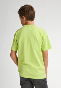 Camiseta de algodón verde neón con cuello redondo y mangas cortas, con un diseño liso sin logos ni gráficos visibles.
