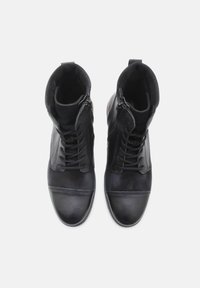 Zapatos altos de cuero negro con un acabado suave, que presentan cordones, cierres de cremallera y un panel texturizado en la punta.