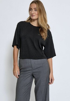 Top corto nero, tessuto strutturato, con un motivo geometrico e maniche corte, abbinato a pantaloni grigi su misura.