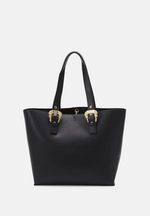 Bolso tote de cuero negro texturizado con dos asas largas y hebillas decorativas doradas cerca del borde superior sobre un fondo liso.