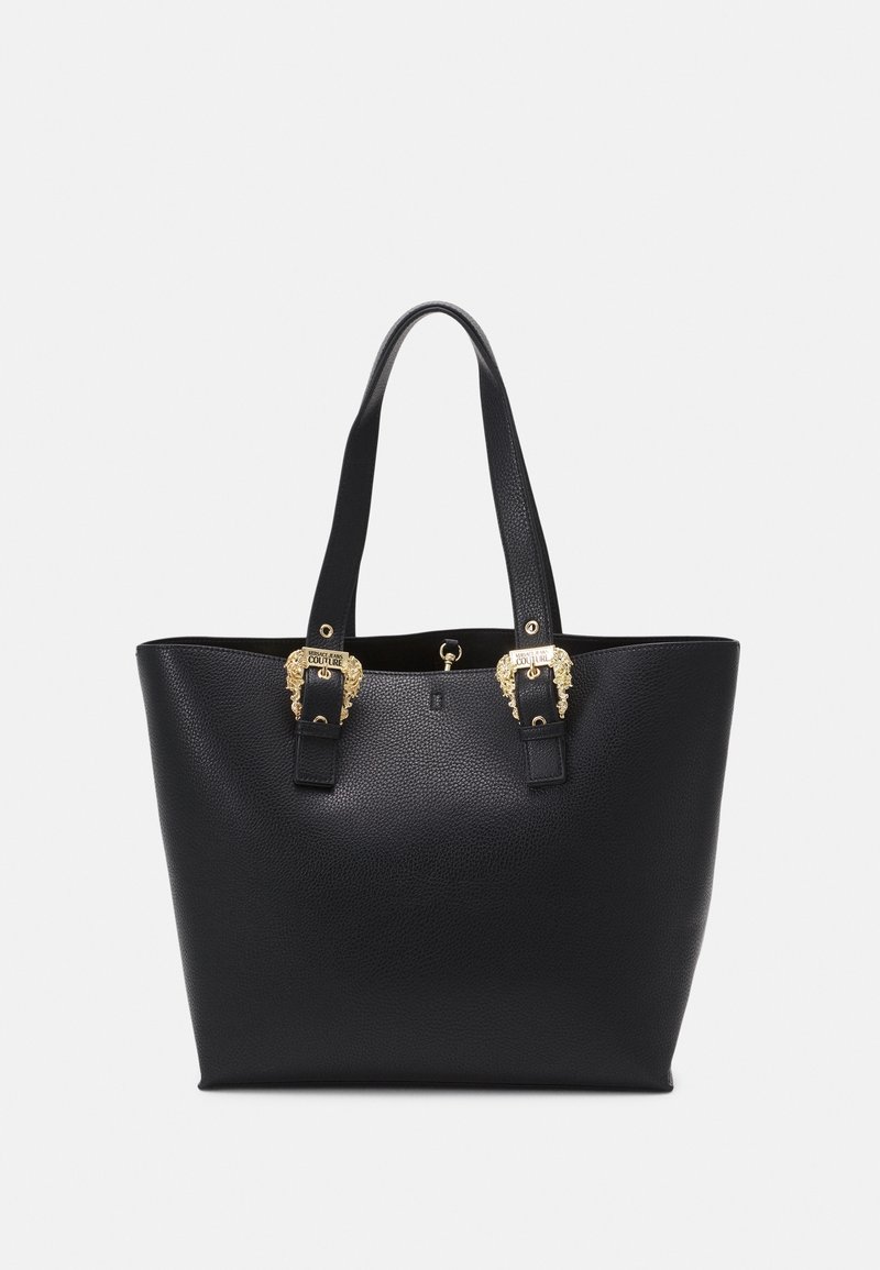 Sac cabas en cuir noir texturé avec deux longues anses et des boucles décoratives dorées près du bord supérieur sur fond uni.