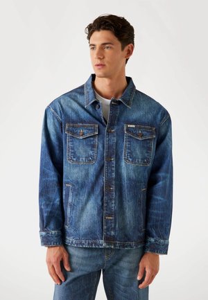 Denim jacket featuring a light to dark blue gradient, two chest pockets, button-up front, and visible stitching on collar and cuffs.