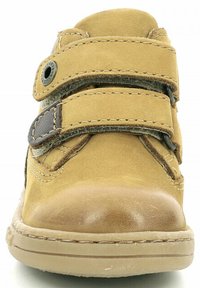 Scarpa in pelle color tan con due cinturini in velcro, punta arrotondata e suola in gomma. Caratterizzata da dettagli di cucitura e un pannello laterale testurizzato.