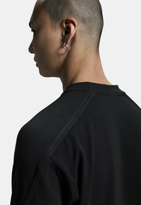 Felpa nera con scollatura rotonda e cuciture sulle spalle a contrasto. Tessuto morbido con maniche lunghe, che mostra un design semplice ed elegante.